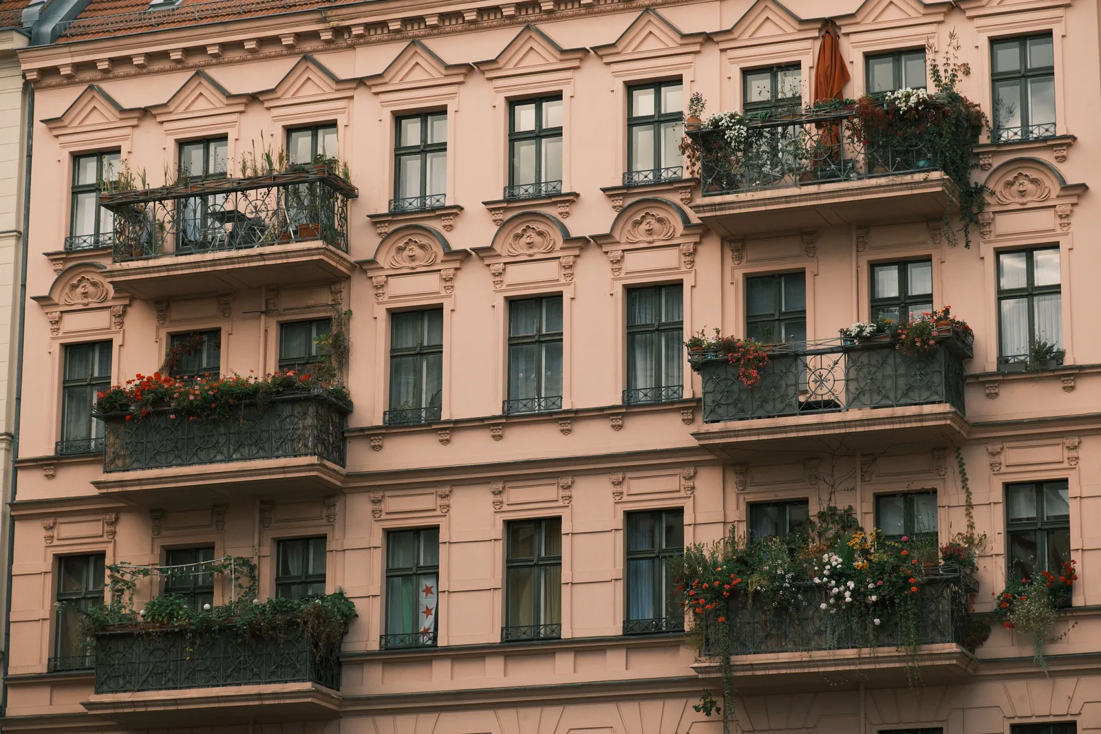 Europäisches Mehrfamilienhaus mit Balkonen und bepflanzten Fensterbereichen